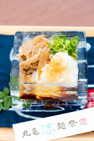  粗く削ったダイコンと甘辛く煮た肉がトッピングされた＜鬼おろし肉ぶっかけ＞が特製の氷の器で提供された