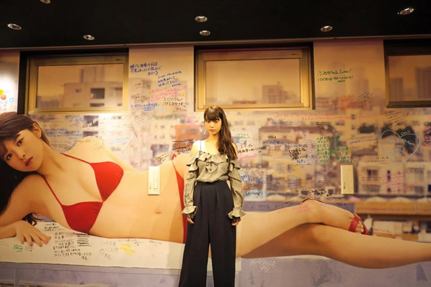  今月いっぱいでリニューアルされる、週プレ酒場内の巨大写真壁紙を前に。握手会に訪れたファンたちが彼女へのメッセージを書き込んでくれた