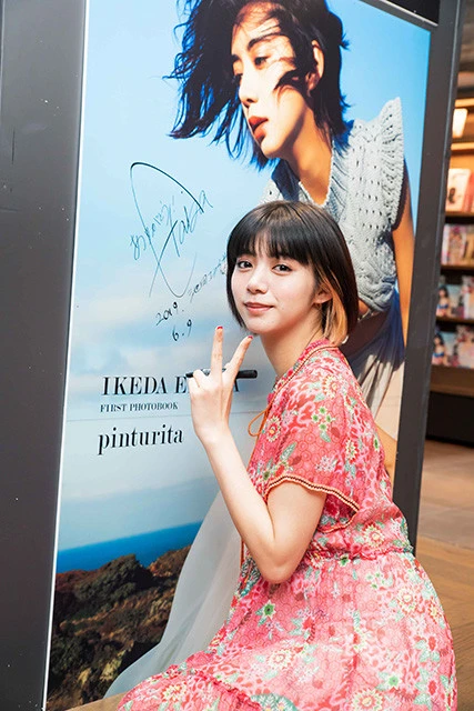巨大な写真パネルにサインをする池田エライザ