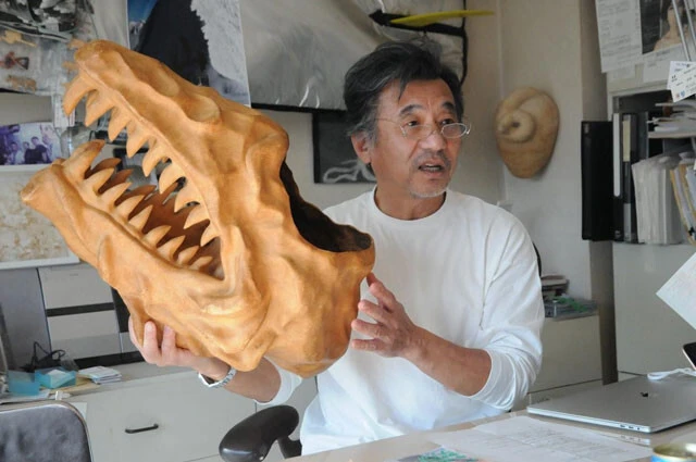 実際に西田氏が制作したという恐竜の模型。新聞紙と粘土で作られているのだとか。西田氏の後ろには、他にも趣味で作ったという工芸品が飾られている。