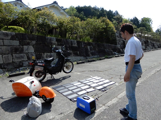 宿場跡近くの休憩所でソーラーパネル2枚(畳2枚分)とソーラーリュックを地面に置き、充電。どう見ても怪しい