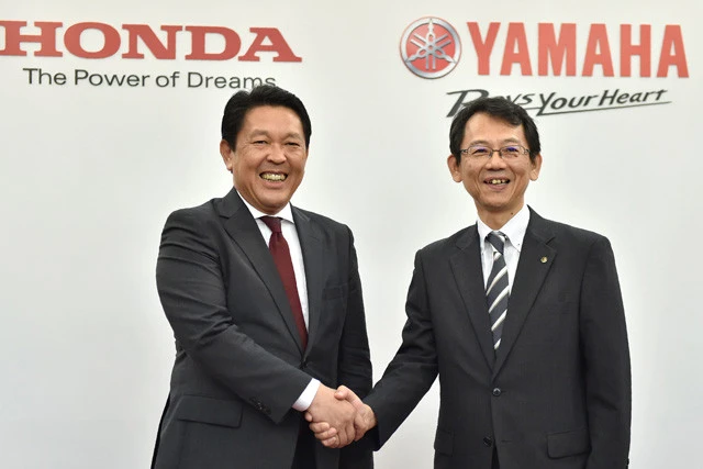 １６年の会見で、握手を交わすホンダの青山取締役（左）とヤマハの渡部取締役（右、肩書は当時）