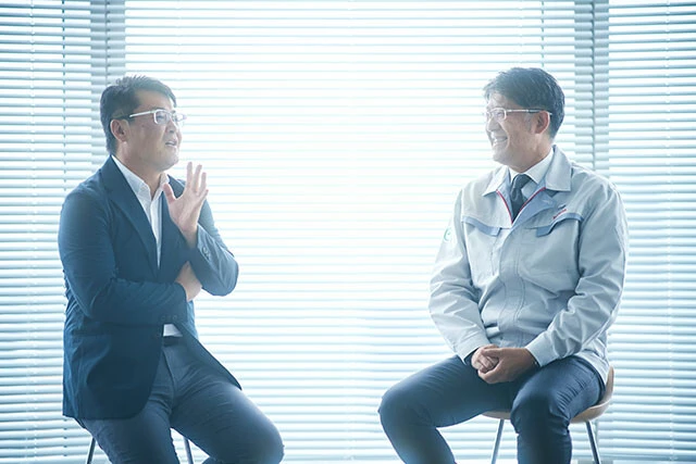 自動車メーカーの元エンジニアのキャリアを持つ山本シンヤ氏（左）。佐藤社長（右）のエンジニアならではの経験談を的確にキャッチし、鬼の深掘り！