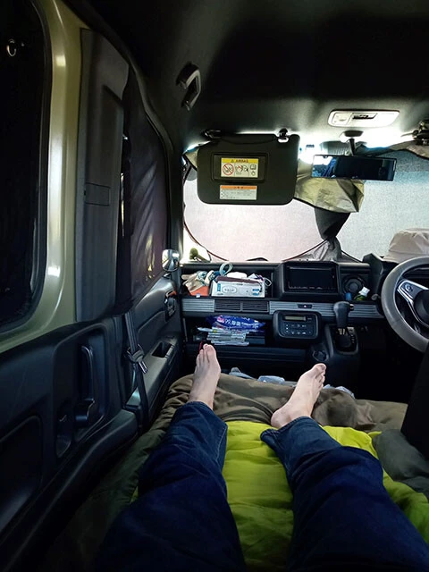 このように足を伸ばせると疲労も軽減。クルマの窓にはプライバシーや防寒のためサンシェードなどを活用