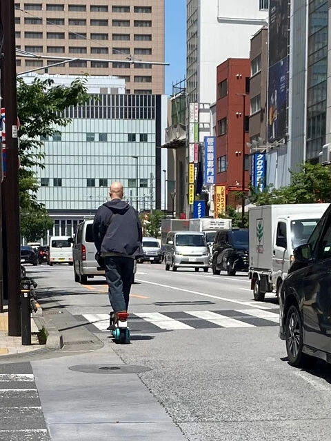 ノーヘルのまま都内の車道を走行する電動キックボード利用者。クルマなどと接触した場合、重大事故につながる危険性は極めて高い