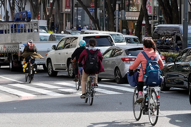 車道を走る自転車利用者。ヘルメットは「努力義務」とされているが、未着用の場合、クルマとの接触時にリスクを伴う