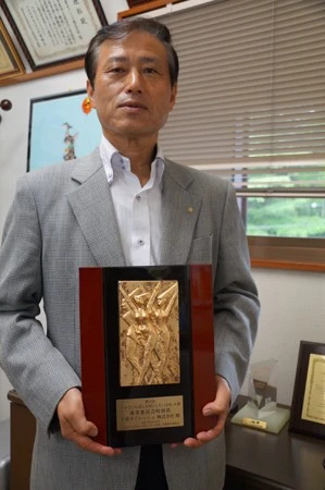 野村社長が手にもつのは社員を思いやる経営が評価されて受賞した「日本でいちばん大切にしたい会社大賞」の表彰盾。「頂けたことは会社の誇りです」