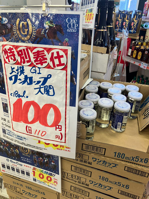 大阪市西成区のあいりん地区にあるスーパー玉出・天下茶屋店では、激安のカップ酒が目玉商品のひとつ。店の前でおっちゃんたちがうれしそうに飲んでいる