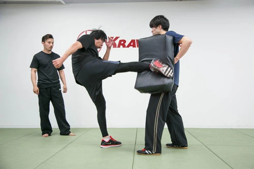 パッドめがけて全力キックの岡村氏(中央)。相手との距離感、体重の乗せ方etc...。単に右足を出せばいいのではなく、左半身をうまく使えてこそ、強烈な破壊力を込めることができるのだ