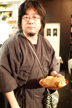 羊肉の猛攻にわれわれの頭はだいぶ曖昧な感じになってきました。そんなさなか、小林氏が完成した料理を片手に登場。この写真だけで見ると、ちょっとジョン・レノンみたいな佇まいですね