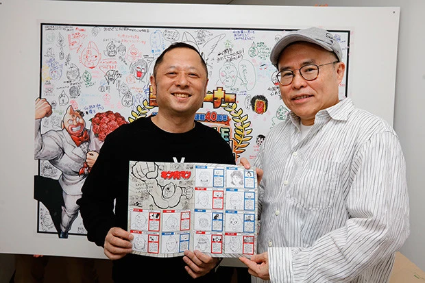 今回プレゼントされた各駅に超人のイラストが描かれたスタンプラリー帳を持つ、ゆでたまご嶋田・中井両先生