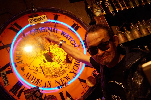 新宿ロフトに今も残る、初期BOØWYのステッカーを指す高橋氏。「この時計、当時はもっと高い所にあったから、布袋のヤツが貼ったんじゃねぇかな?」