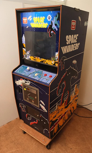 78年、タイトーによる後期型・純正アップライト筐体。外装に描かれたロゴに宇宙人、UFO、惑星の表面のイラストが時代をしのばせる。当時、筆者は6歳。背が低いために画面に届かずプレイ不可で、心折れた記憶あり／ナツゲーミュージアム所蔵