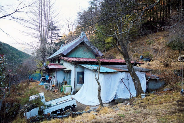 東出が生活している北関東の山奥にある山小屋の外観。白いシートで囲われている部分で主に生活している