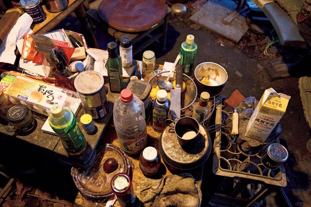 醤油やこしょう、オリーブオイルなどが無造作に置かれたテーブル。室内でたき火をしているので灰が少しかぶっている