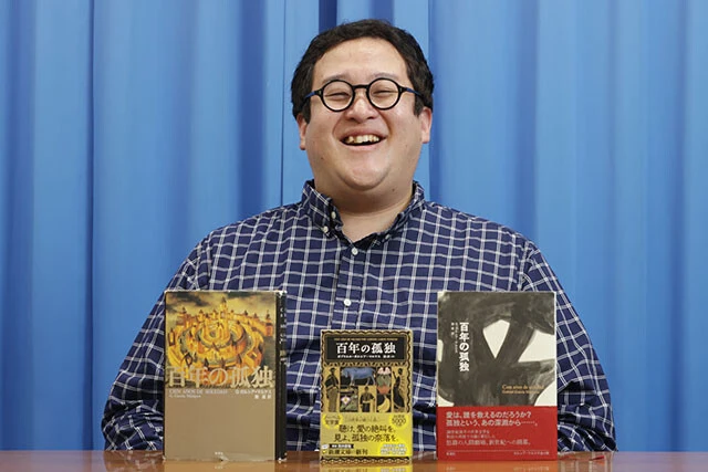 さまざまなバージョンの『百年の孤独』たちに囲まれて、恍惚の表情を見せるぐんぴぃ氏。左は1999年刊行の単行本(ぐんぴぃ氏私物)、右は2006年刊行の単行本、中央が最新版である文庫本