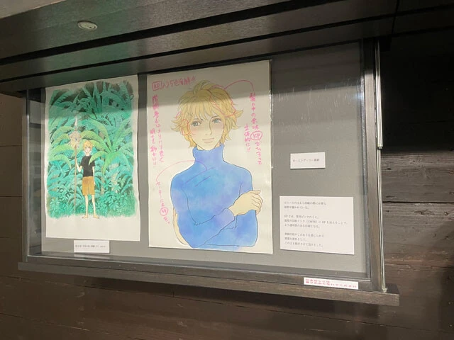 中央は2007年に発行された『モーニング・ツー』2号に掲載された表紙イラスト（W表紙のうちの裏表紙）。イラストはビニールに入っており、その上には印刷のための指示が書き込まれている。印刷のこだわりまで伺える珍しい展示