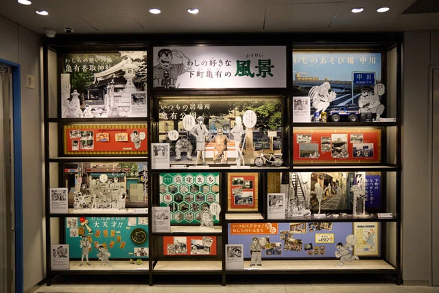 2階から1階に下る階段の途中に飾られている亀有の観光名所パネル。『こち亀』と亀有との一体感を演出している