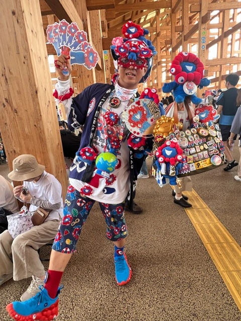 ミャクミャクバッジがいっぱいついたカバンを持つあんばーさん（仮名）