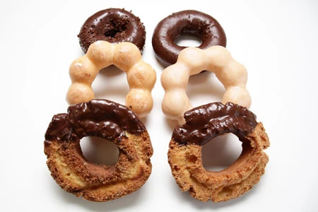 左列がミスド。値段はセブンより高めも、安定のうまさ! よくやる“100 円セール”時には行列も。セブンはミスドよりもやや小ぶりながら価格は安め。工場で作られた商品を、店内の専用陳列ケースで販売する