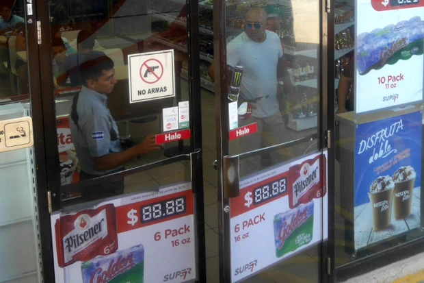 左の男性。肩にライフル下げてます。ドアには銃持ち込み禁止マーク