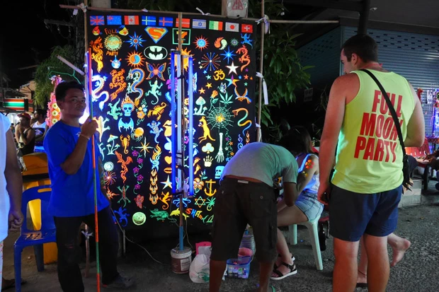 黒い布に蛍光ペイントで描かれたイラストから好きなものを選んで体に描いてもらうのだ