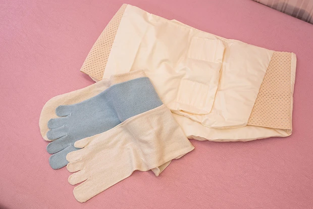  『全国冷え症研究所』開発の対策グッズ。上「羽毛腹巻き」（８５３２円）、下「３足重ねばき靴下」（２５９２円）は５本指のシルクと綿の靴下と一番上に重ねるシルクの靴下がセットになっている