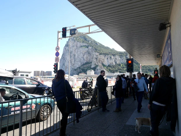 飛行機が通り過ぎるのを踏切前で待つ人々