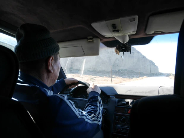 ヒッチハイクの車内。運転手はおじいちゃん。アメリカの荒野のような景色の中、車を走らせる