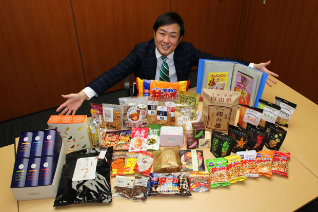 柿ピーを前に笑顔の中倉氏だが、実際はパッケージがちゃんと見えているか胸中は不安…。家には300コ以上の柿ピーが保管されているそう
