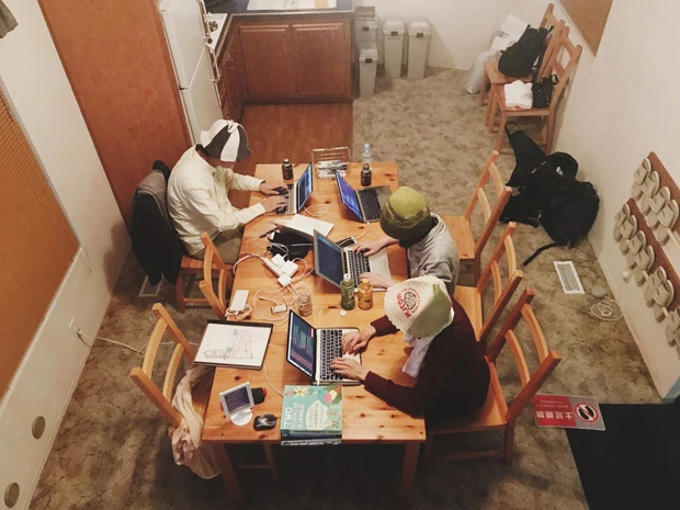 サウナ施設で開発合宿をするメンバー。サウナハットをかぶってPCに向かう