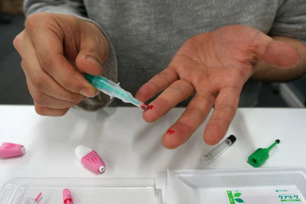 自身の指に針を刺して採血する