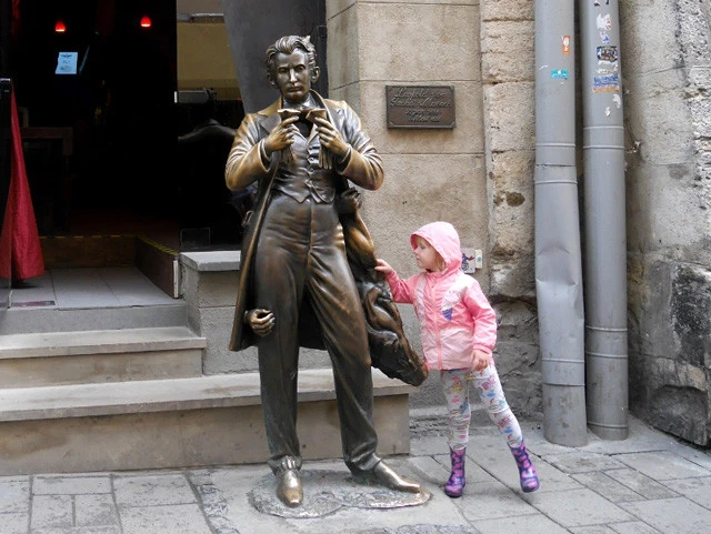 マゾッホのコートに掴まり、ズボンのポケットの奥を覗く子供