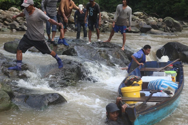 タビン川を木製の小型船でさかのぼる。川は茶色く濁っている。時折、大木や石が行く手を阻めば、全員で協力して首まで川に漬かりながらボートを押す