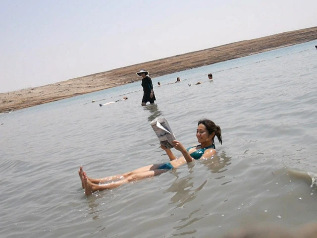 死海で浮きながら新聞を読むベタな写真