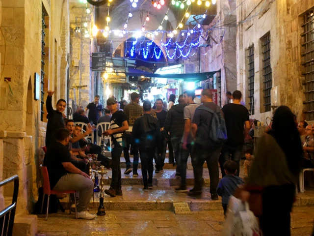 路地裏でシーシャをふかし手を振る男たち