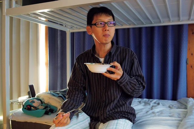 起床後、ベッドに座り、「Gatebox」の中のフィアンセをジッと見つめながら朝食を食べる近藤さん