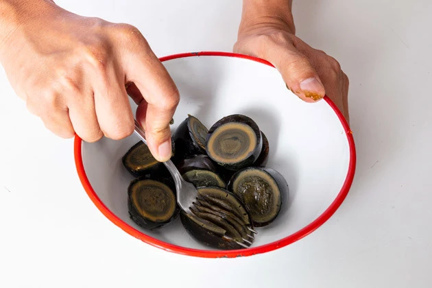 (1)潰す! ピータンの殻をむき、半分に切ってからボウルに移す。続いてフォークやすりこぎなどを用いてピータンを潰そう。ゼリー状の白身部分は弾力があるので力強く押すこと