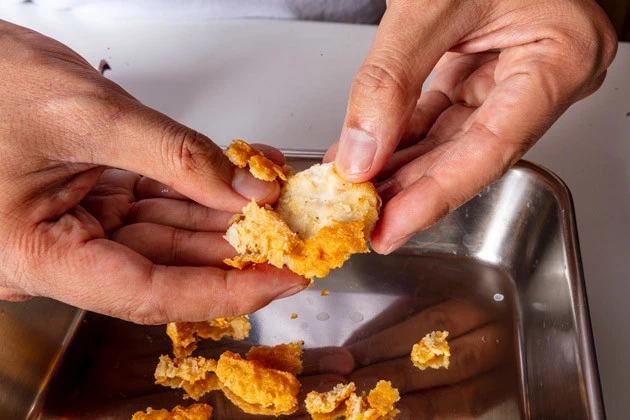 (1)剥がす! チキンマックナゲットの衣を手で地道に?がし、肉と衣を分けた状態にする。衣を?がし終えたらすりこぎなどを使い、ひき肉状に戻していくイメージで肉を潰していこう