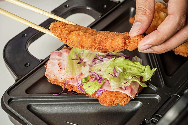 (1)のせる! ホットサンドメーカーにファミチキを置き、その上に具をのせてもう1個のファミチキで挟む。具はサンドイッチの定番から甘いものまでなんでもOK。好きな食材を挟んでみよう