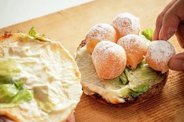 (2)挟む! てりやきマックバーガーを開き、解体したポン・デ・シュガーを挟めるだけ挟もう。上手にバンズを押さえながら豪快にかぶりつくべし。味も食感も食べ応えも抜群!