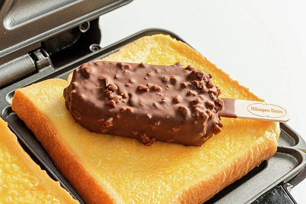 (2)のせる! ホットサンドメーカーに卵を吸収させた食パンをのせ、さらにその上にハーゲンダッツを置き、さらに食パンをのせる。デセールバーを使う場合はあらかじめ棒を抜いておこう