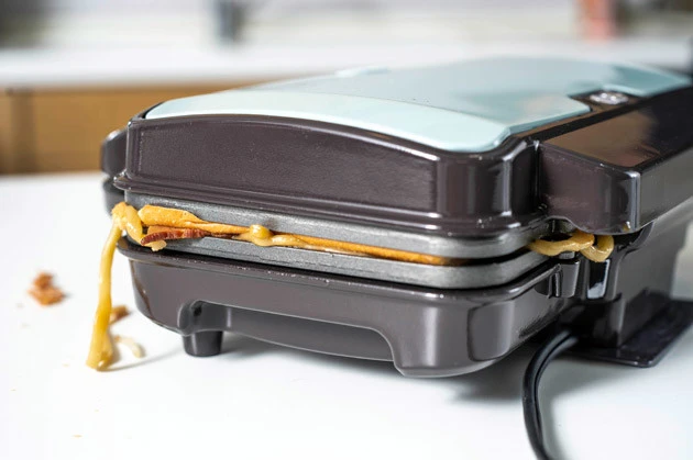 (2)焼く! 食パンをもう1枚のせたら、強引にホットサンドメーカーのフタを閉めて焼き上げる。多少はみ出ても問題ないが、機械が壊れないように注意。まねする場合は自己責任で!