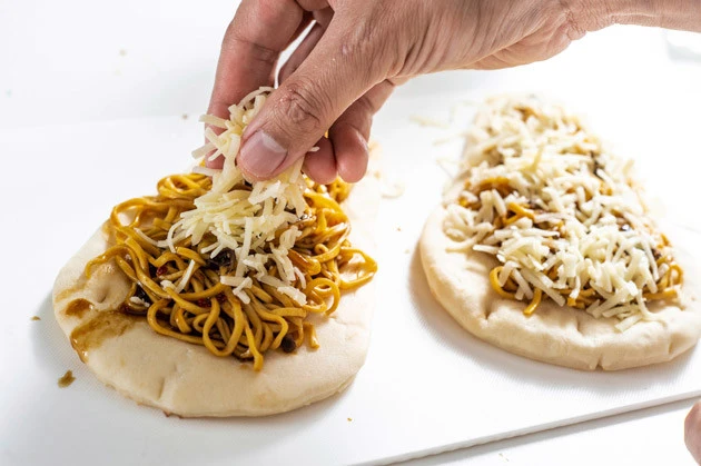 (2)チーズ! 麺の上からスープを垂らし、その上にとろけるチーズを盛りつける。スープを多くすれば辛味が強くなり、チーズが多いとマイルドになるのでお好みに合わせて調整しよう