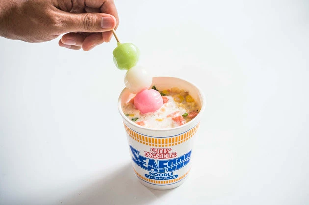 (4)投入! パステルカラーの三色団子とシーフードヌードルの青いロゴがとってもキュート。インスタ映え間違いなしだ。団子の串で麺をすくい、麺と団子を絡めて食べてもよい
