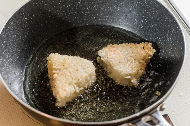 (2)揚げる! フライパンで油を熱し、おにぎりを投入して揚げる。色がつかないのでわかりにくいが、もともとはそのまま食べられるものなので、表面が硬くなったら取り出して油を切る