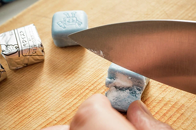 (2)開く! スーパーソーダガムをまな板の上に載せ、包丁を使ってガムの端5mmくらいの位置を切り開く。まな板と包丁、そして自分の手はできる限り乾燥させた状態で作業すること