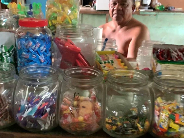 上半身裸の店主が店番をしている駄菓子屋