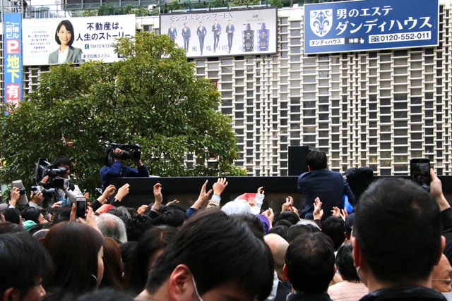 号外を求めて、押し寄せ手を掲げる人々。なかには喫煙所の壁に登る人まで