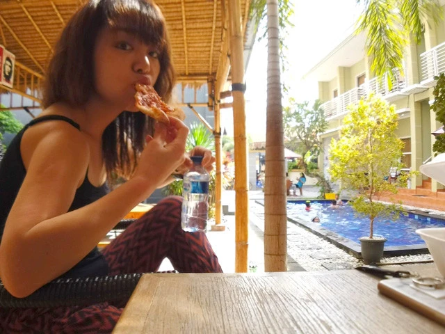 安宿にてもらい物のピザに食らいつくスッピンの旅人